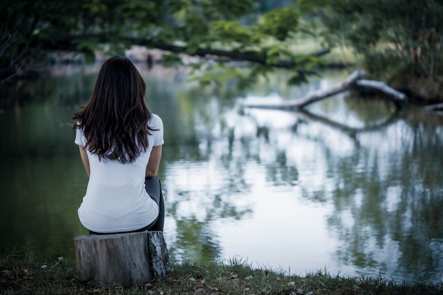 池のそばに悲しそうに座っていた女性うつ病は家族や対人関係に大きな影響を与えます プレミアム写真