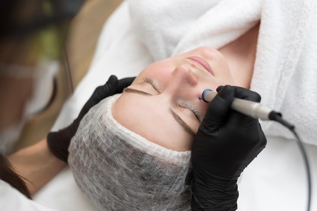 Premium Photo Therapist Beautician Makes A Laser Treatment To Young Womans Face At Beauty Spa