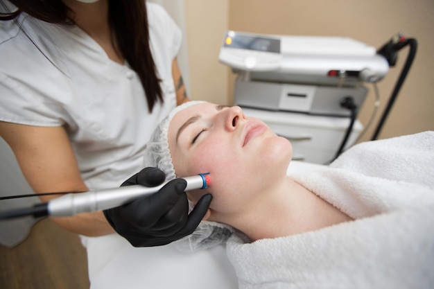 Premium Photo Therapist Beautician Makes A Laser Treatment To Young Womans Face At Beauty Spa