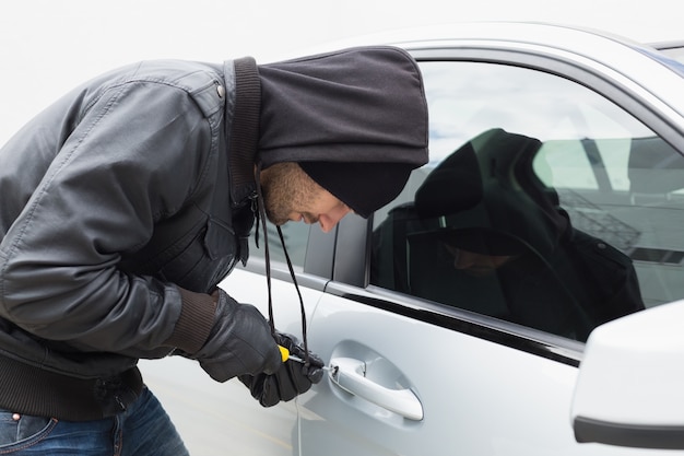 Premium Photo | Thief breaking into car with screwdriver