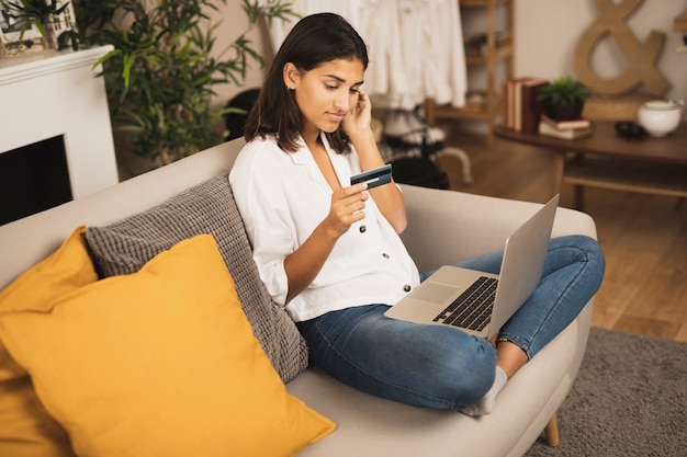 Free Photo | Thinking woman looking at a credit card