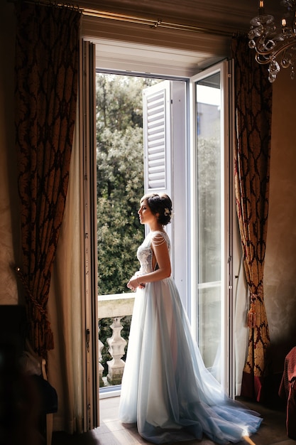 Thoughtful bride stands before an open window in the morning Photo ... Open Window At Morning