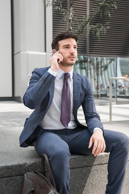 Free Photo | Thoughtful guy in suit talking on smartphone