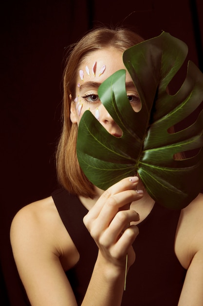 Free Photo | Thoughtful woman with flower petals on face and leaf