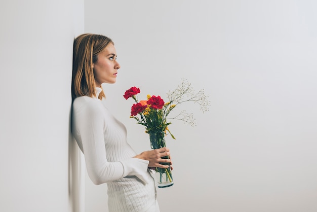 壁に花瓶に花を持つ思いやりのある女性 無料の写真