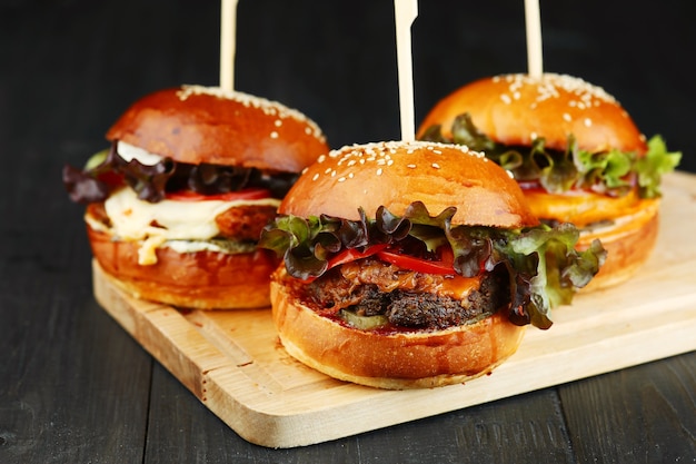 Premium Photo | Three burger on wood. set of burger on wooden deck closeup.