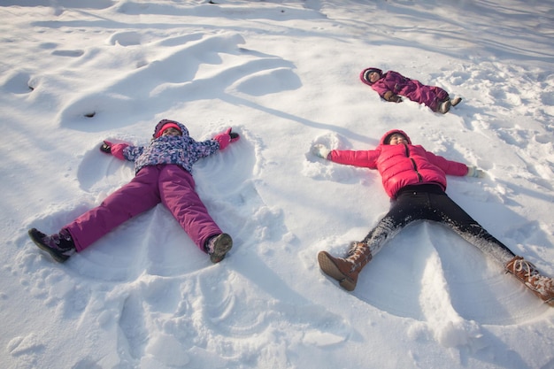 Premium Photo | Three children make snow angels in winter sunny day