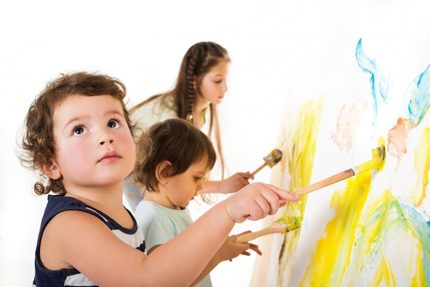 Premium Photo | Three children paint with brushes and paints