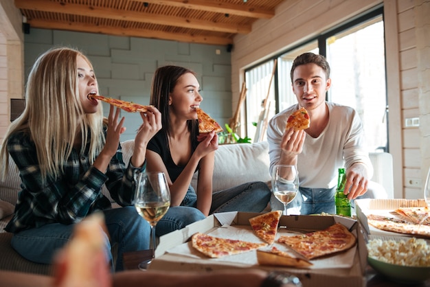 Premium Photo | Three friends eating pizza in house