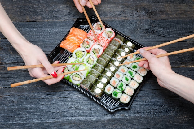 Three hands with chopsticks and sushi set. Premium Photo