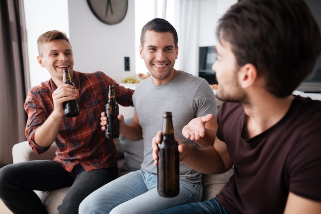 Premium Photo | Three men drink beer from dark bottles.