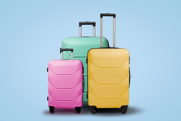 Premium Photo | Three multi-colored plastic suitcases on wheels on a ...