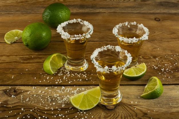 Premium Photo | Three tequila shots with lime and salt on the wooden ...