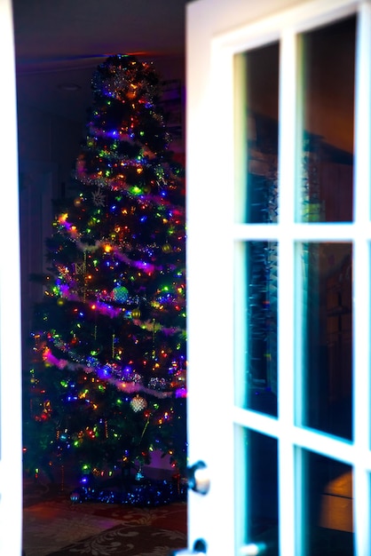 Premium Photo | Through an open door christmas tree with colorful lights.