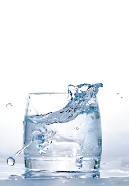 氷をコップ一杯の水に投げ入れた プレミアム写真