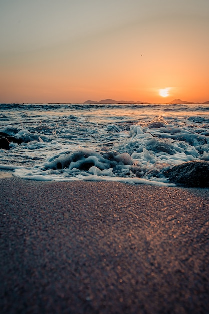 premium-photo-tides-breaking-in-the-sand-of-the-beach-during-a-sunset