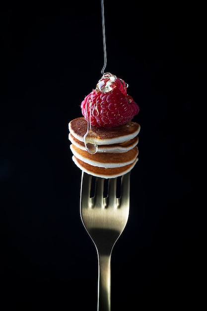 Premium Photo | Tiny cereal pancakes with raspberries strung on a fork ...