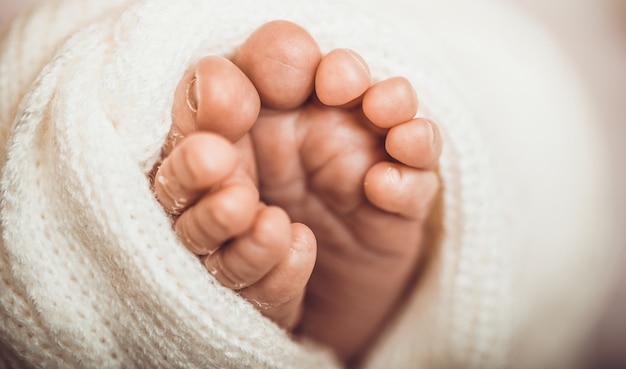 生まれたばかりの赤ちゃんの小さな足 ピンクの毛布に対して柔らかい新生児の足 つま先を丸めて赤ちゃんの女の子の足 プレミアム写真
