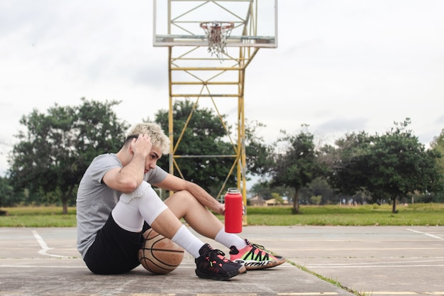 premium-photo-tired-young-man-sitting-on-an-abandoned-basketball-court