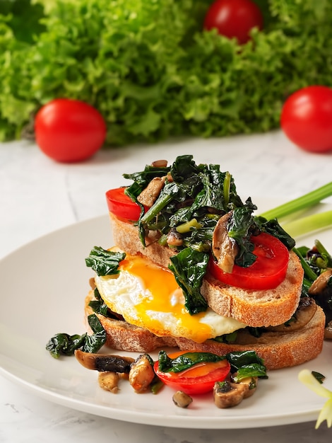 Premium Photo Toast With Scrambled Eggs On Toasted Bread With Spinach Mushrooms And Tomato On A Gray Plate Close Up Fried Egg For Breakfast