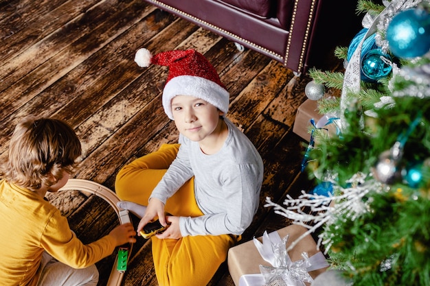 鉄道を建設し クリスマスツリーの下でおもちゃの列車で遊ぶ幼児の男の子 クリスマスプレゼントの子供たち クリスマスの時期 プレミアム写真