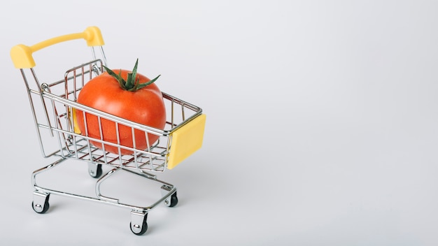 Premium Photo | Tomato in shopping cart on white surface