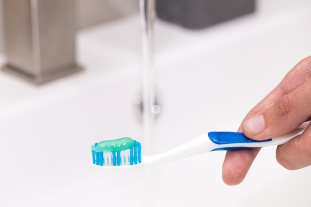 Premium Photo | Toothbrush with toothpaste in the guy's hand on the ...