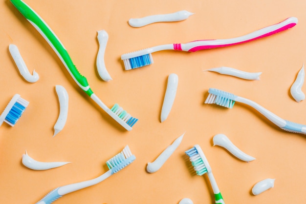 Toothpaste with different type of toothbrushes on colored background Free Photo