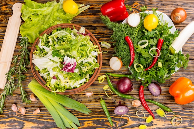 Top down view of rosemary, lettuce, leek, onion, peppers, lemon and other delicious ingredients on wooden table Premium Photo