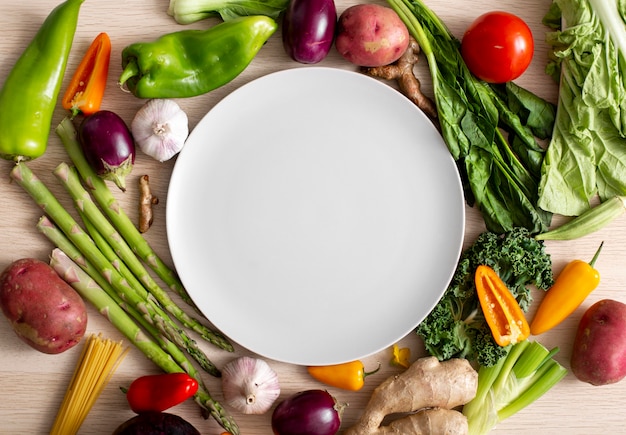 Top view assortment of veggies with empty plate Free Photo