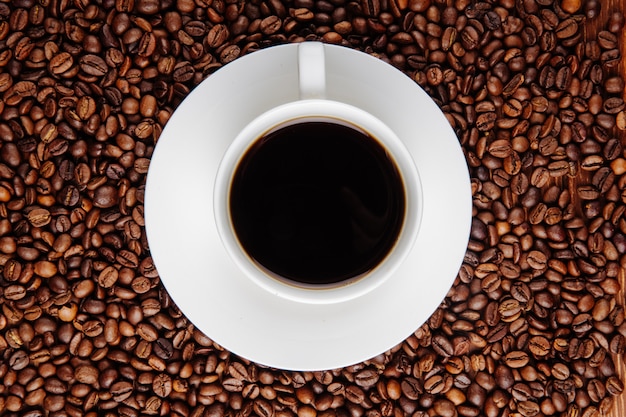 Free Photo | Top view of a cup of coffee on coffee beans background