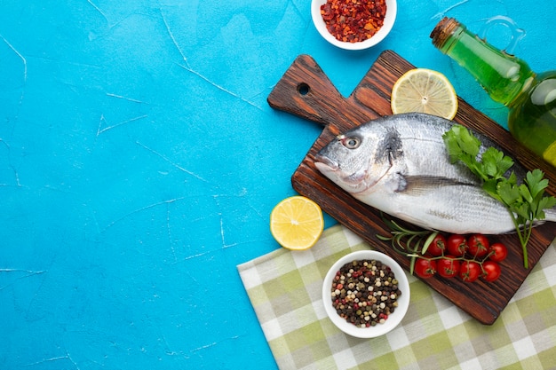 Top view fresh fish with condiments on table Free Photo