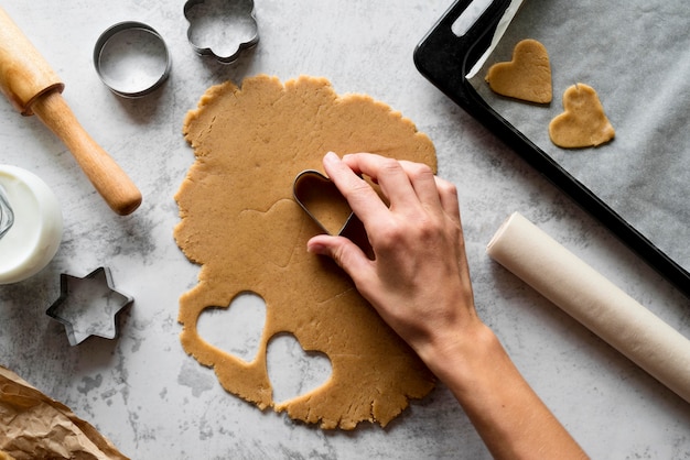 Free Photo | Top view hand cutting dough with shapes