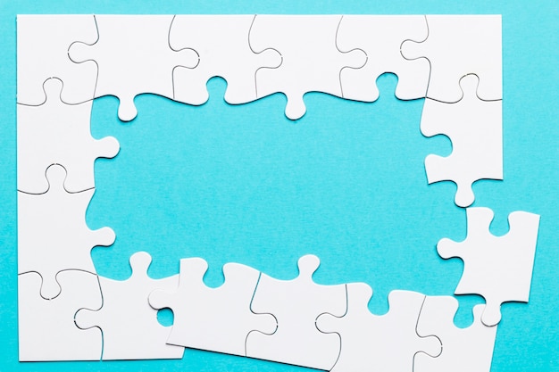 Top view of incomplete puzzle frame over blue backdrop Free Photo
