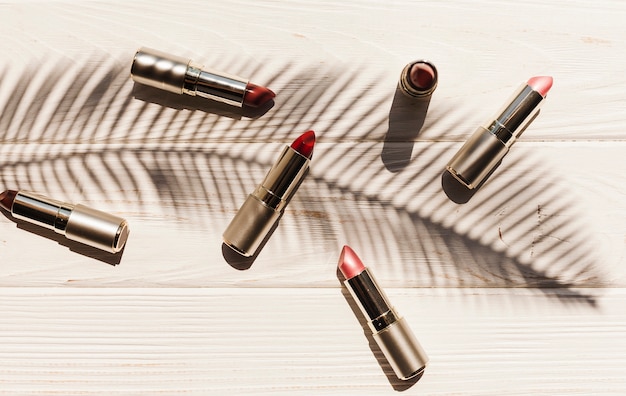 Top view lipsticks with palm branch shadow Free Photo