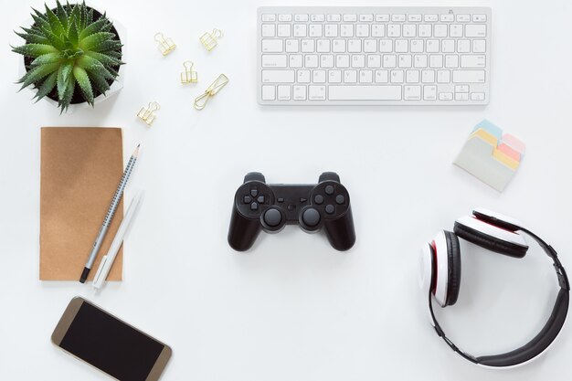 Top view of mobile phone, computer keyboard, notebook, flat lay with joystick and gamepad, game console, headphones Premium Photo