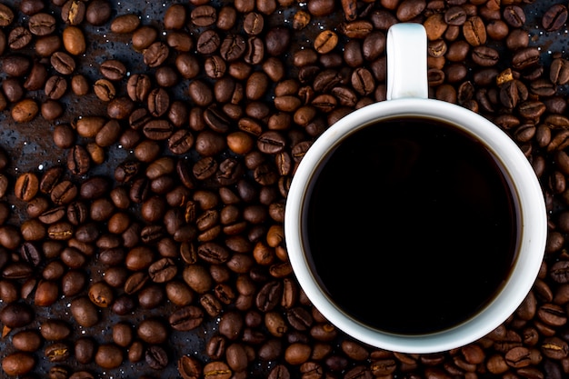 茶色のローストコーヒー豆の背景にコーヒーカップのトップビュー 無料の写真