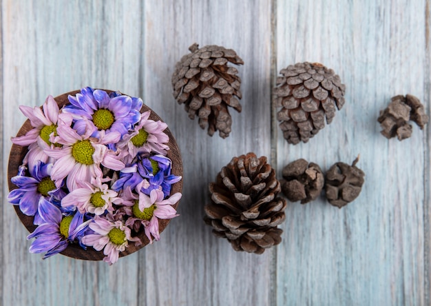 木製の背景にボウルと松ぼっくりの花の上面図 無料の写真