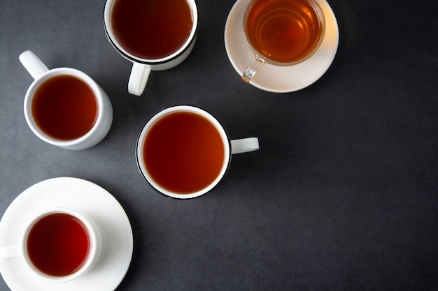 top-view-of-many-cups-mugs-with-hot-tea-drink-on-dark-copyspace-tea-time-or-tea-brake-autumn-beverage-toned-image-with-tea-cups_4740-1779.jpg