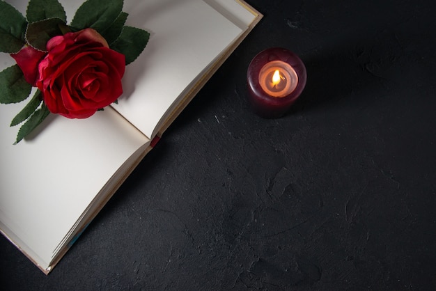 暗い壁にキャンドルと赤い花が開いた本のトップ ビュー 無料の写真