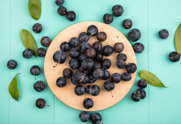 青色の背景に木製キッチンボード上の小さな酸っぱい黒っぽい果物のスローのトップビュー 無料の写真