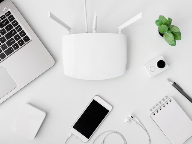 Top view of office desk table with notebook, plastic plant, laptop, smartphone and modem router Premium Photo