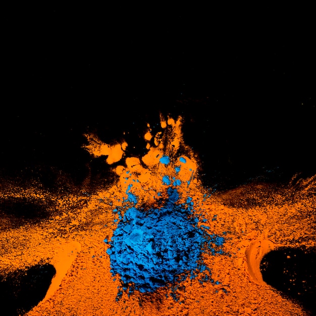 Free Photo | Top view of orange and blue holi colors over black surface