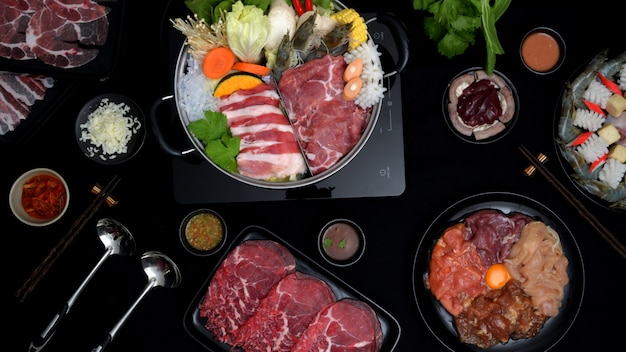 Top view of shabu-shabu in hot pot, fresh sliced meat, sea food ...