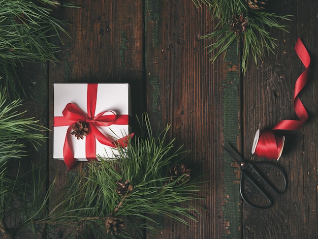 Top view of white box decorated red ribbon with fir and pine cones tree Premium Photo