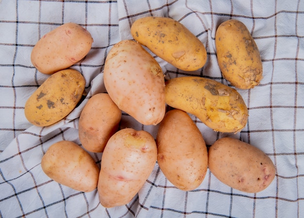 Top view of white yellow and russet potatoes on plaid ...