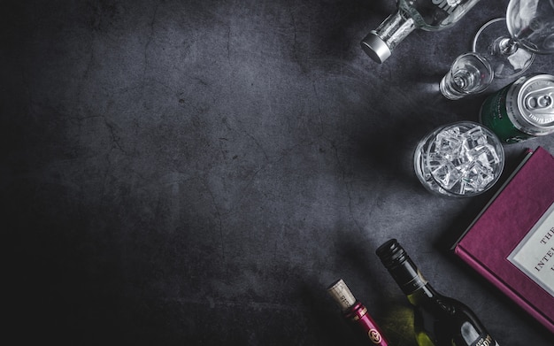 Top view of wine bottle, vodka bottle, ice cube, beer, and corkscrew Premium Photo