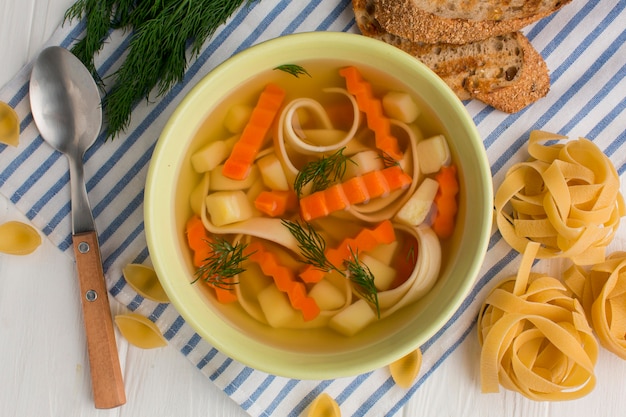 Top view of winter vegetables soup in bowl with tagliatelle and toast Free Photo