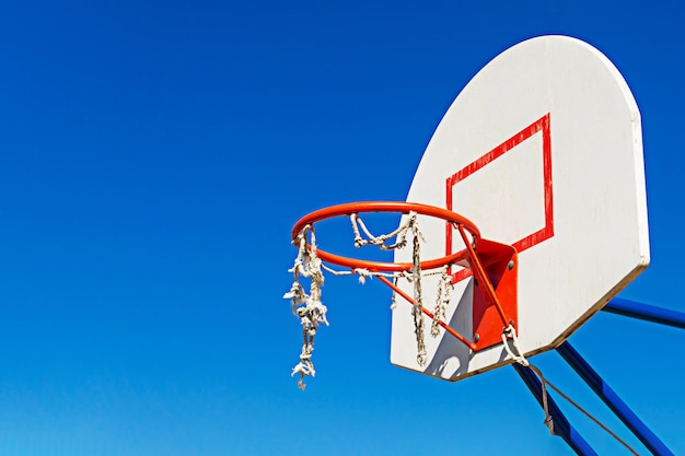 Premium Photo | A torn basketball basket against the blue sky.