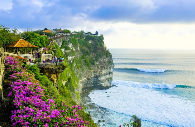 Tourists stand at sunset and admire the scenery on a cliff near the uluwatu temple on the island of bali, indonesia Premium Photo